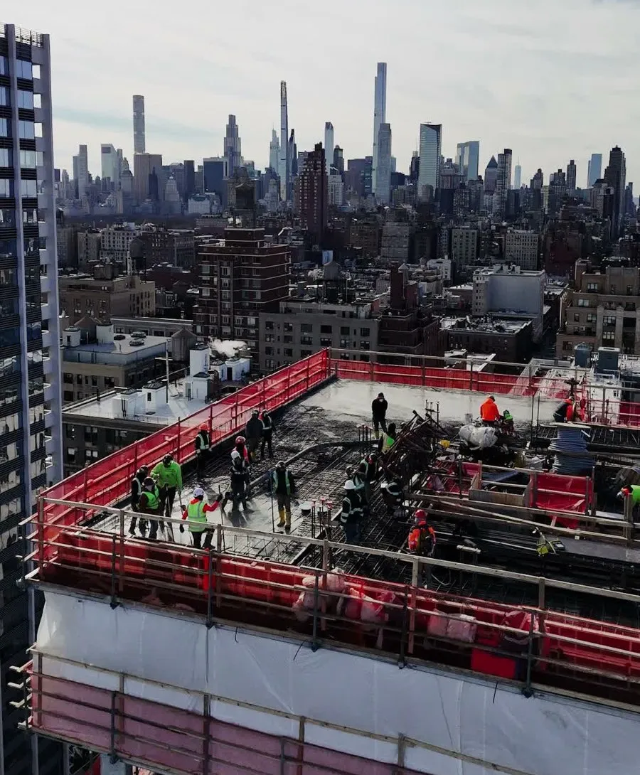 A drone photo of a construction site rooftop, Midtown Manhattan skyline behind it